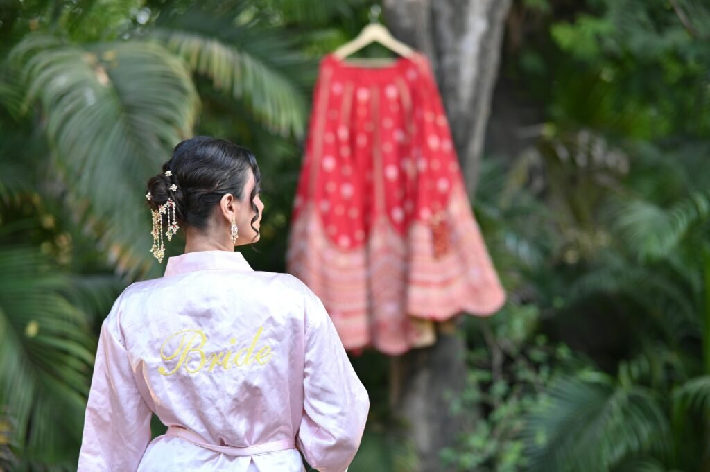 A bride viewing her traditional red wedding dress hanging in a lush garden.